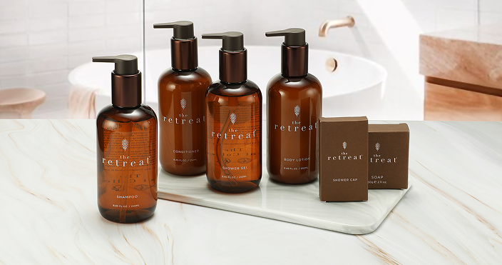 The Retreat by Celebrity Cruises full bath amenities set including shampoo, conditioner, body lotion, and shower gel on a marble tray.